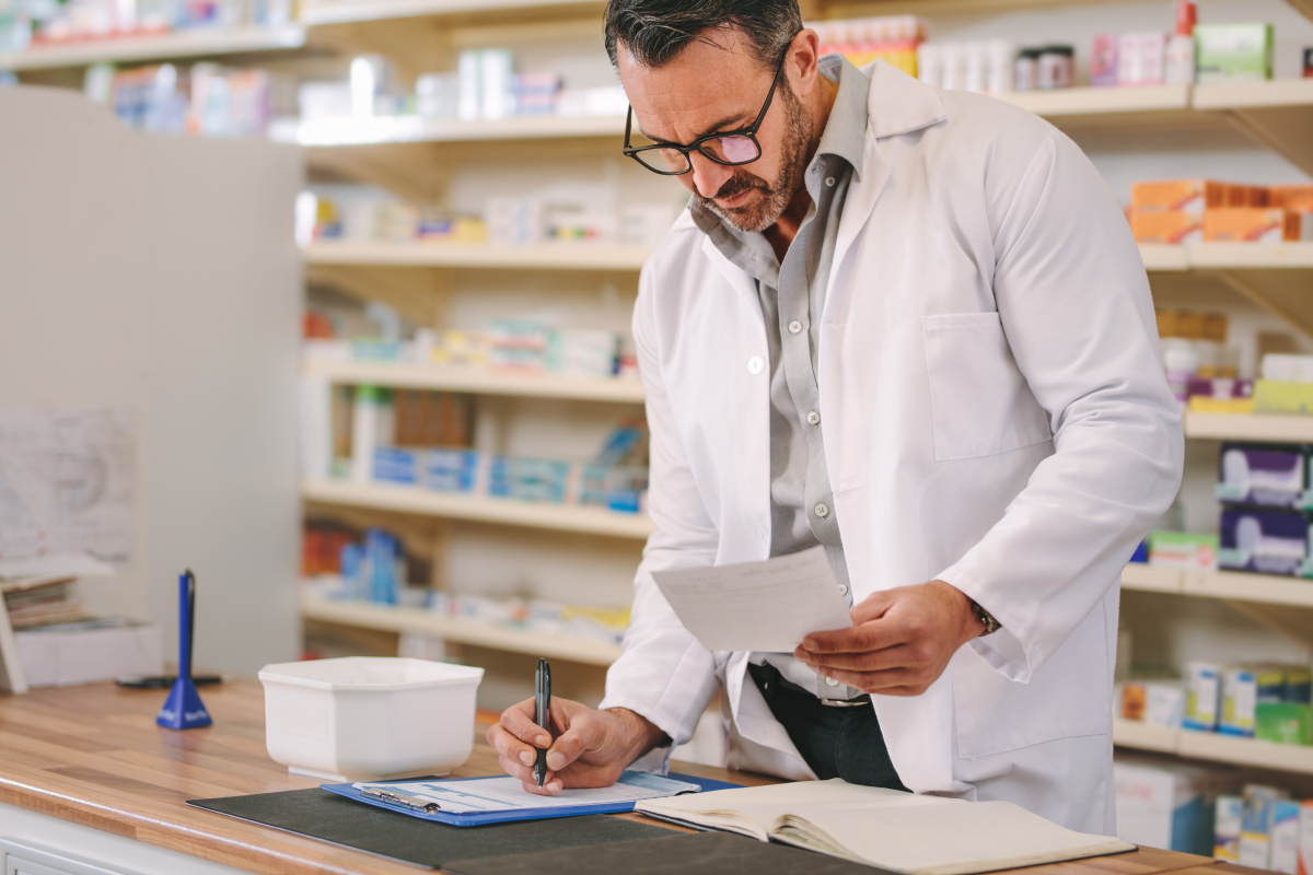 Farmaceuta przy pierwszym stole wypełnia dokumenty, takie jak sprawozdanie zd-5