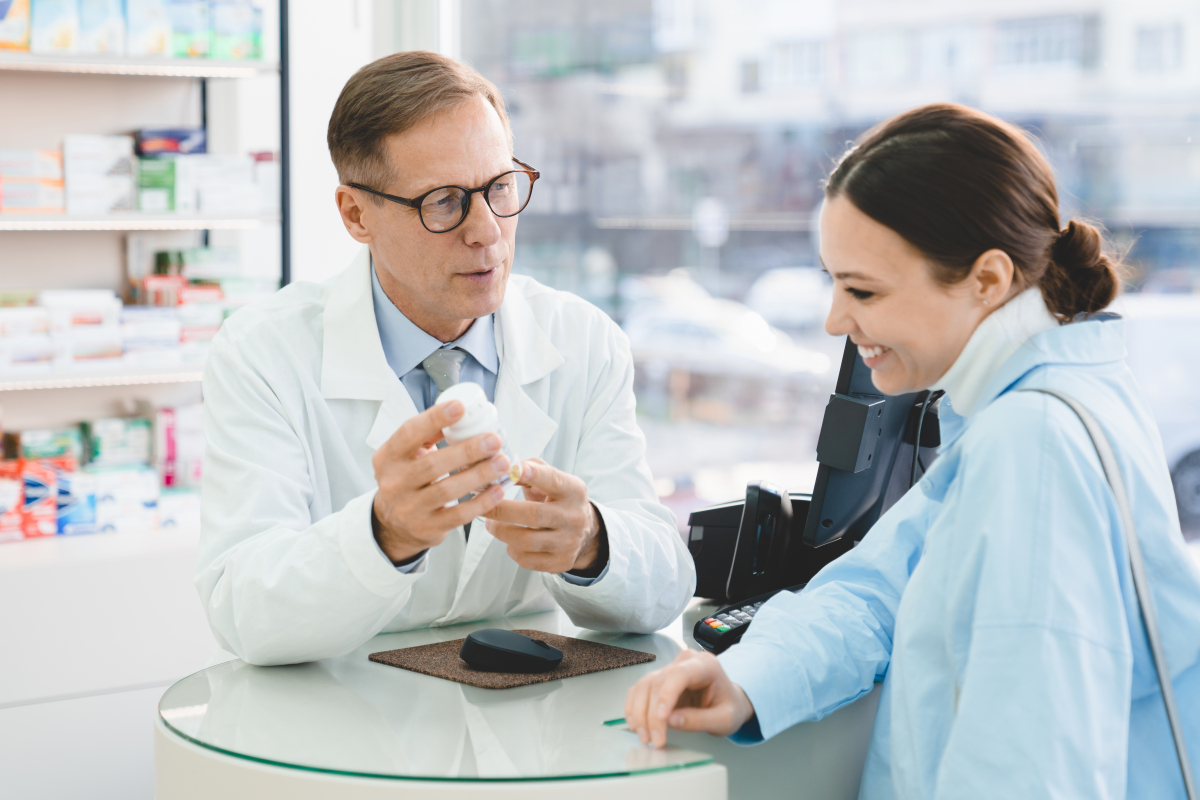 Farmaceuta pokazuje pacjentce opakowanie leku.