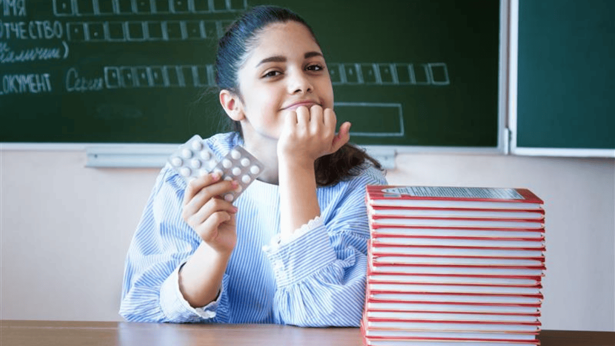 Dziewczynka w szkole trzymająca blistry z tabletkami (fot. shutterstock.com)