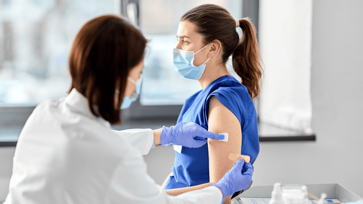 Farmaceutka przyklejająca plaster kobiecie po szczepieniu (fot. shutterstock.com)