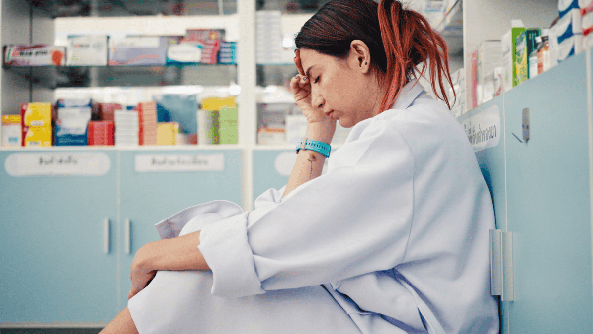 Załamana farmaceutka siedzi na podłodze w aptece (fot. istockphoto.com)