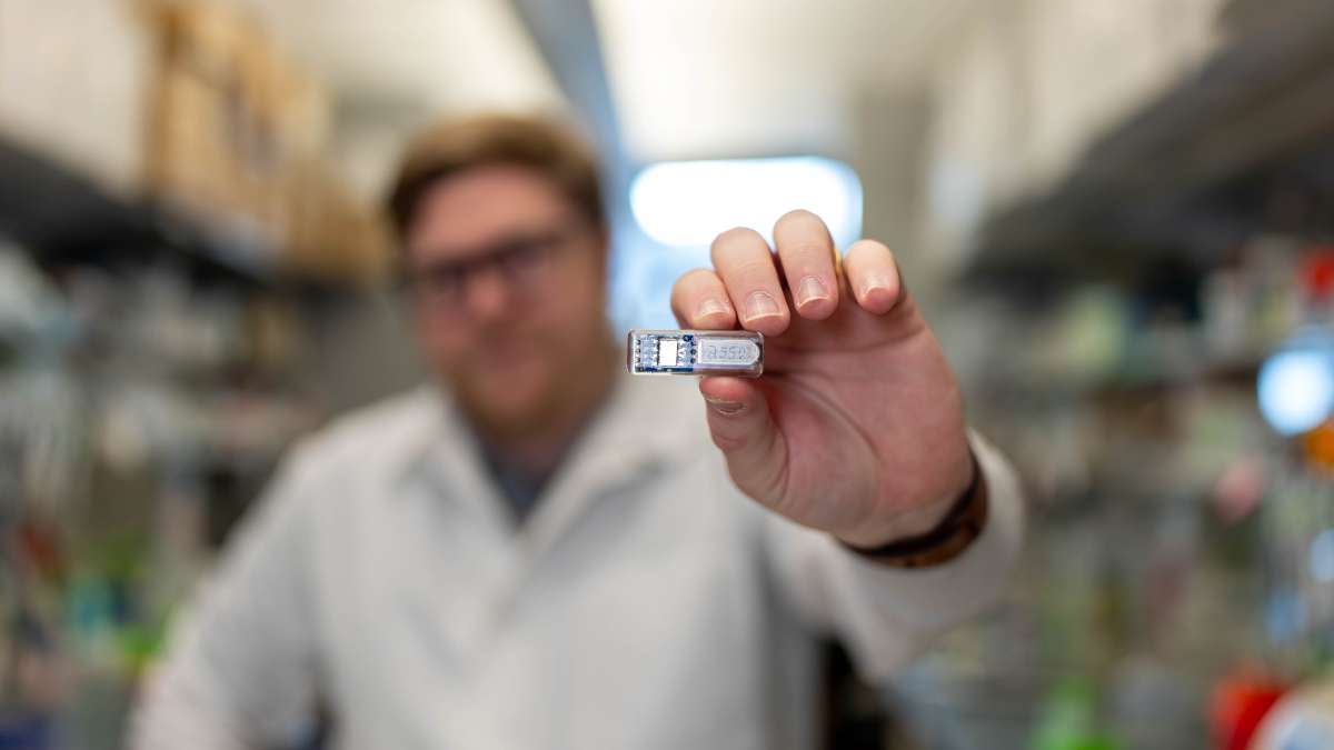 Chris Wright, student studiów doktoranckich na Rice University, trzyma w rękach implant „żywej apteki”.