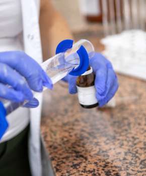 Farmaceuta nalewa płyn z kolby do butelki