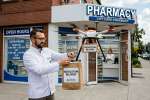Farmaceuta zawiesza paczkę z lekami pod drona