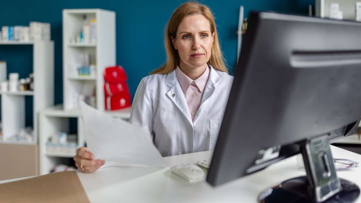 Farmaceutka w biurze pracuje przy komputerze z dokumentami