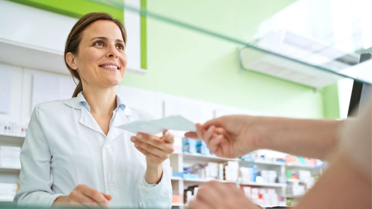 Farmaceutka wręcza pacjentowi receptę